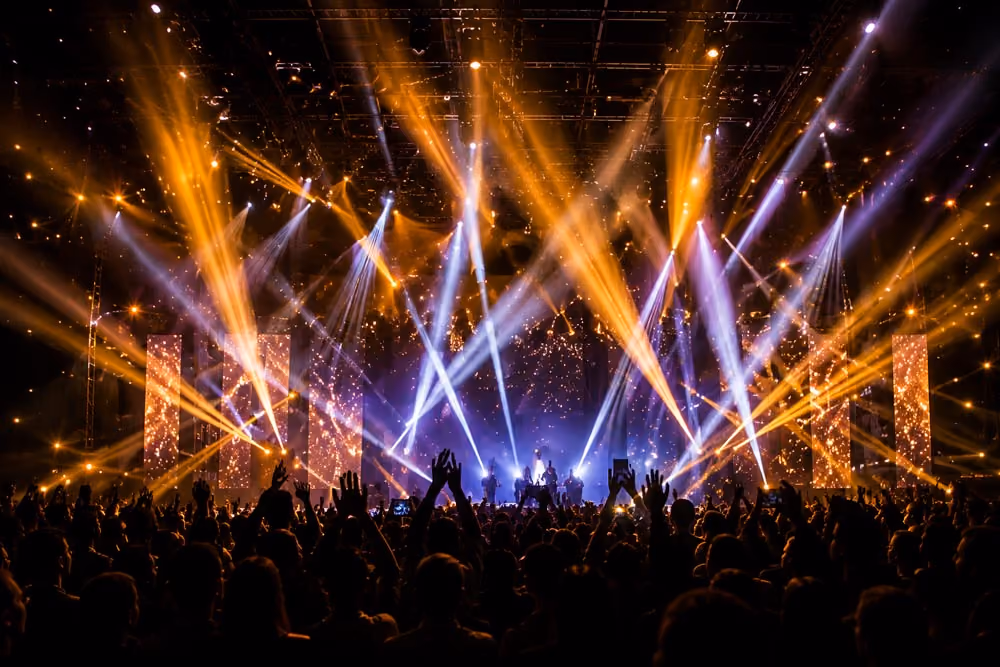 Amber and violet beams sweeping over a packed arena crowd